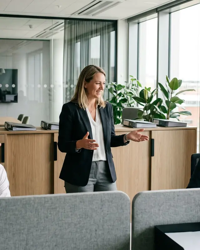 Une responsable échange avec deux collaborateurs dans un centre de gestion moderne.