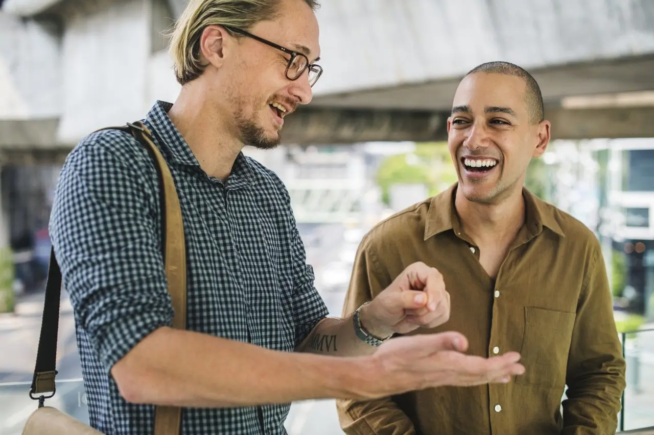 Deux amis discutent et rient joyeusement ensemble en extérieur.