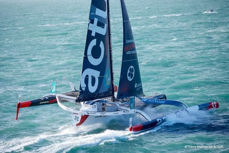 Le trimaran de course Actual Ultim 3 navigue à vive allure sur l'océan.