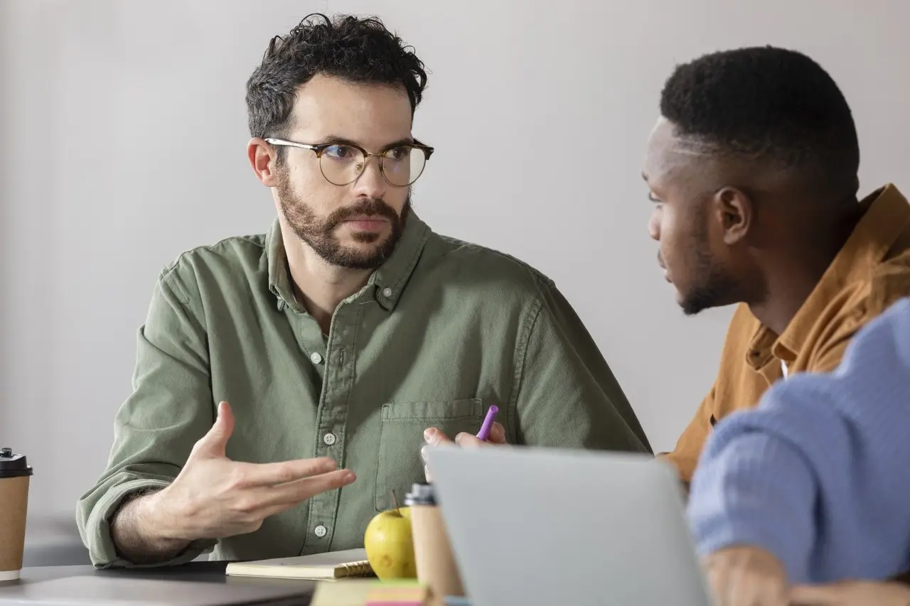 Deux professionnels échangent au bureau lors d'un bilan de compétences.