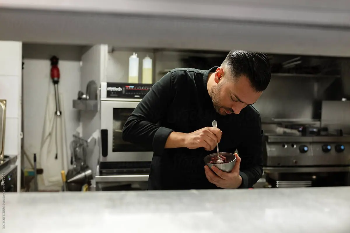 Un cuisinier professionnel prépare minutieusement un plat dans la cuisine d'un restaurant.