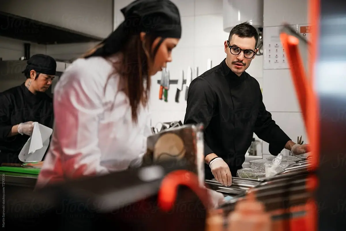 Des cuisiniers s'activent en cuisine au sein d'un établissement de restauration.