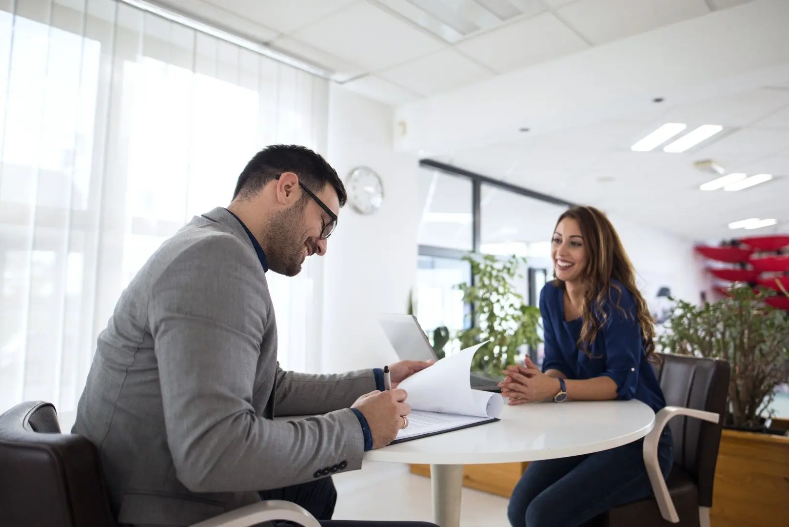 Un recruteur prend des notes face à une candidate souriante lors d'un entretien d'embauche.