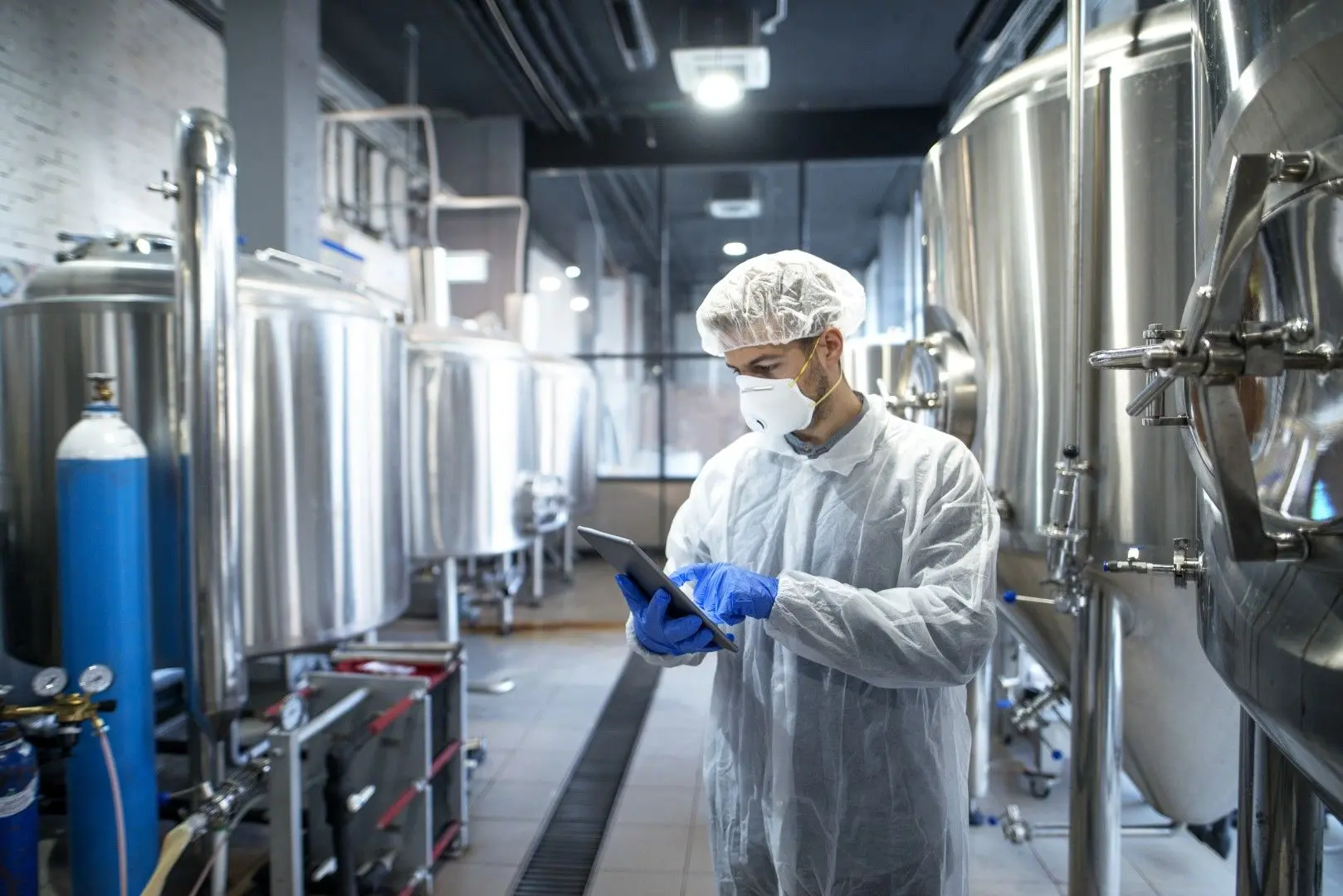 Un conducteur de ligne équipé contrôle la production sur sa tablette au sein d'une usine agroalimentaire.