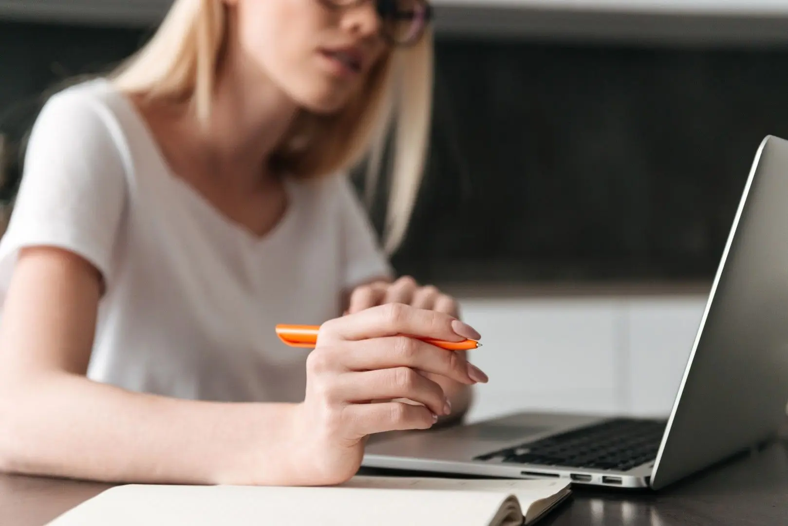 Une femme se prépare à un test de recrutement devant son ordinateur portable, un stylo à la main.