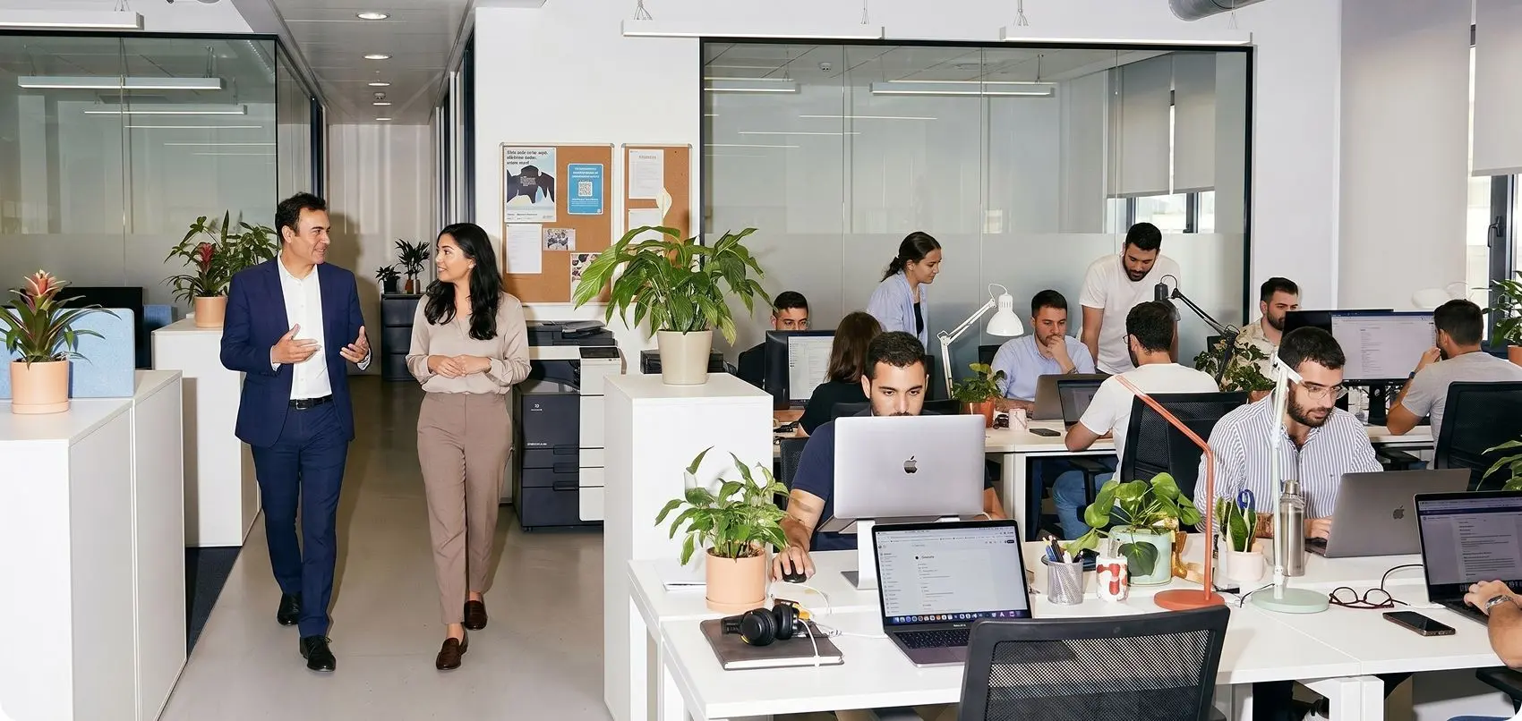 Des collaborateurs échangent et travaillent dans un bureau moderne en open space.