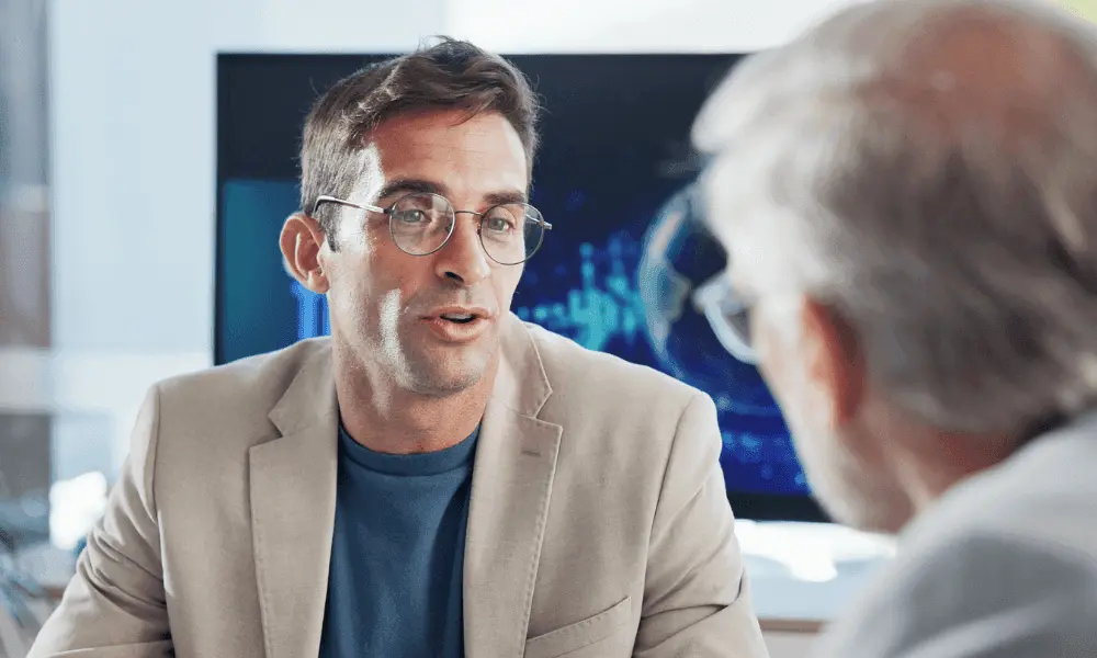 Un professionnel à lunettes échange avec un collègue lors d'un entretien de travail.