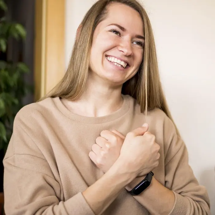 Une jeune femme souriante, les mains sur le cœur, exprime sa motivation.