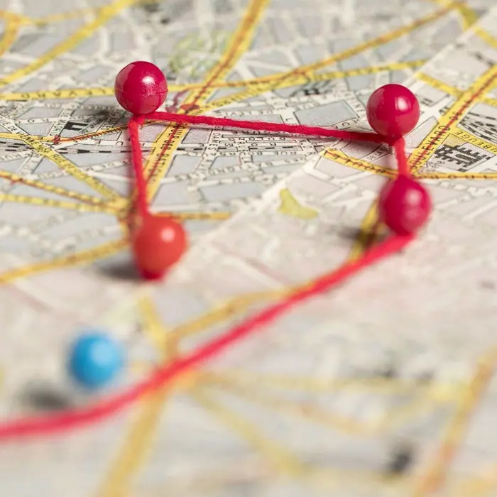 Carte de ville avec des punaises reliées par un fil rouge pour trouver une mission près de chez soi.