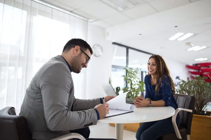 Un recruteur prend des notes face à une candidate souriante lors d'un entretien d'embauche.