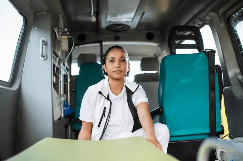 Une ambulancière en uniforme assise dans son ambulance de secours.